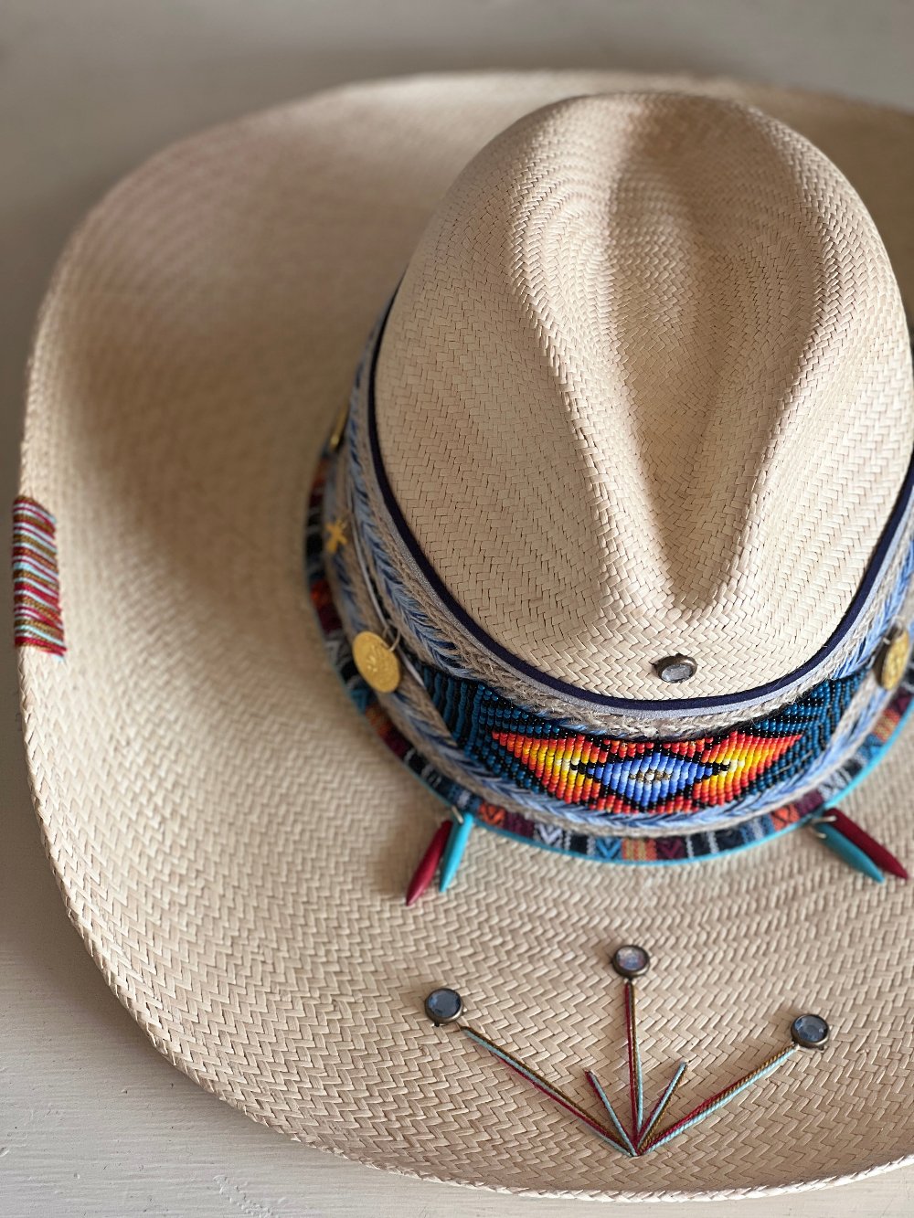 White woven hat, with a thick lace piece displaying a unique mosaic made of beads at the front