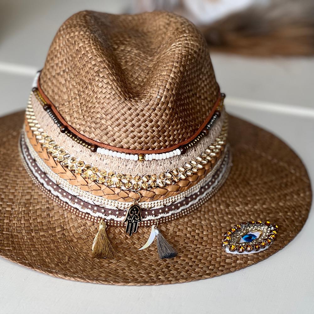 Woven brown hat, with several intricate and colorful details at the base of the crown and string markings at the top