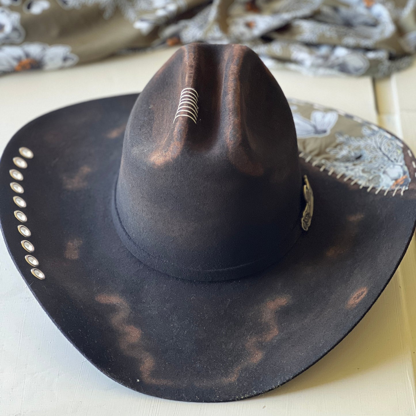 Black cowboy hat with decorative band on a white surface
