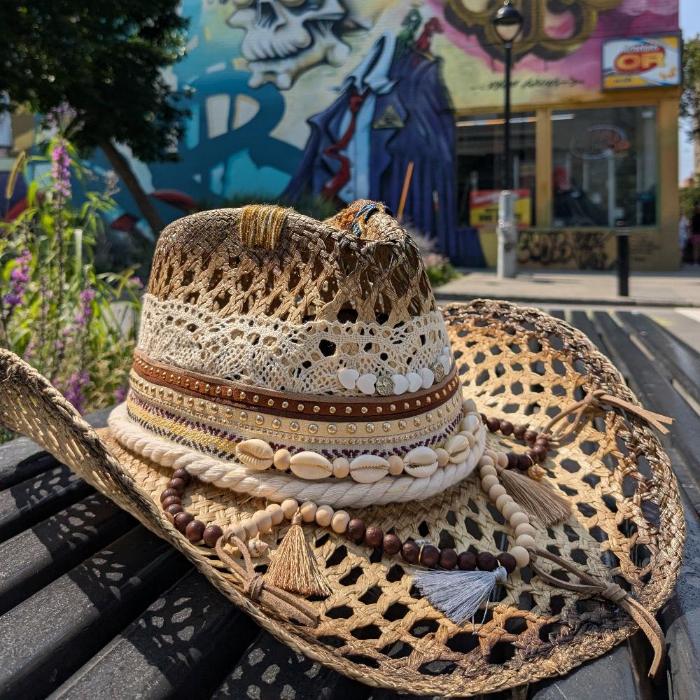 Woven white hat, with several intricate and colorful details at the base of the crown modeled in a western style