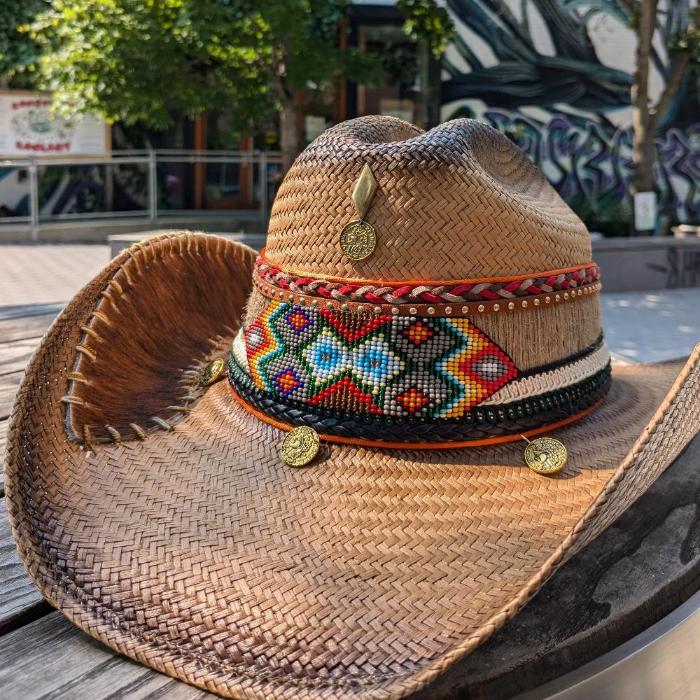 Woven brown hat with a bead mosaic at the base of the crown modeled in a western style
